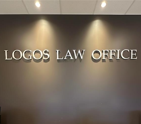 Dimensional lettering reading Logos Law Office on the reception wall, lit by two ceiling spots